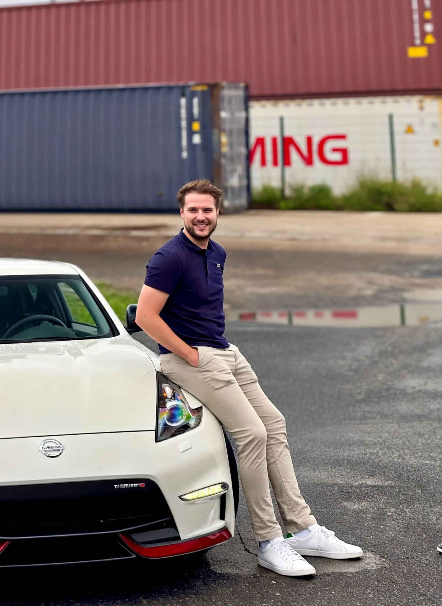 Alexandre « Alejkz » BERTRAND au Havre, assis sur sa Nissan 370Z Nismo blanche, devant des conteneurs